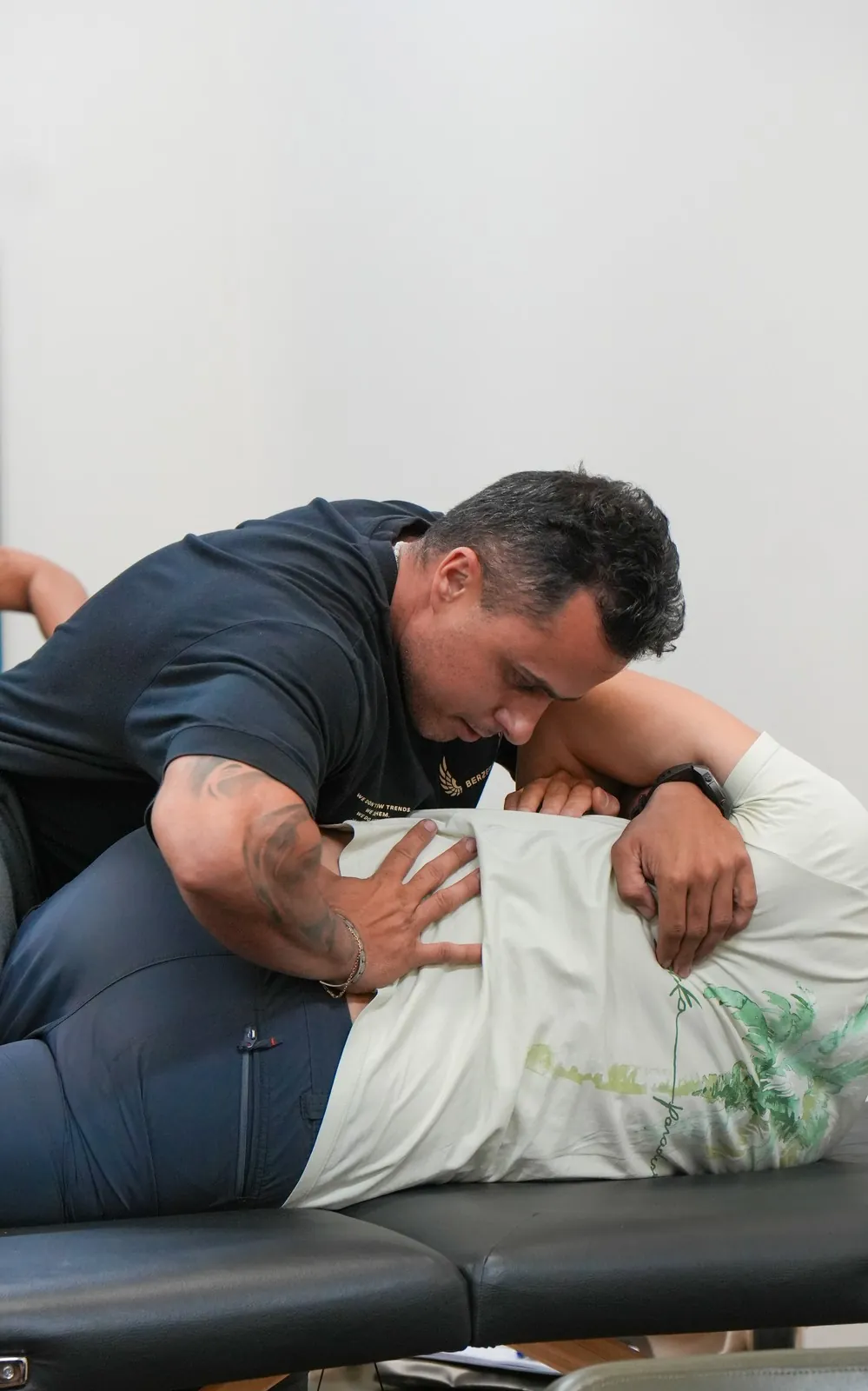 Guilherme Leal, de perto, ajustando o quadril e a região lombar de um paciente deitado de lado